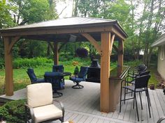 a wooden gazebo sitting on top of a patio next to a table and chairs