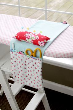 an ironing board with scissors and fabric on it sitting next to a window sill