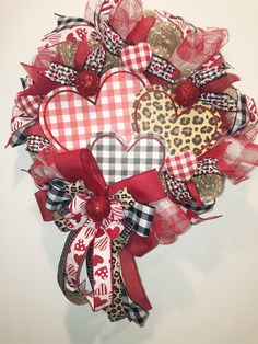 a heart shaped wreath with leopard print and red ribbon on the front, hanging on a white wall