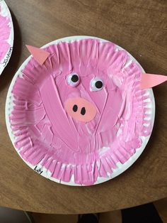 a paper plate with a pink pig face on it and two other plates in the background