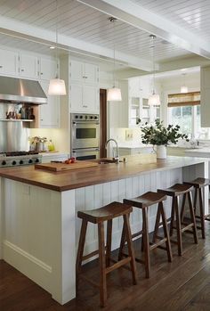 a kitchen island with stools in front of it and an open floor plan on the wall