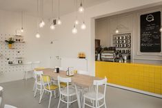 the interior of a coffee shop with yellow and white chairs, tables, and shelves