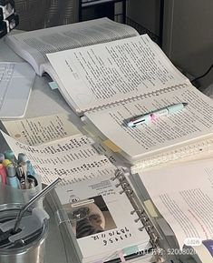 an open book sitting on top of a desk next to a cup and computer keyboard