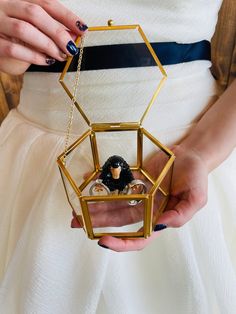 a woman in white dress holding an ornament with two small dolls inside it