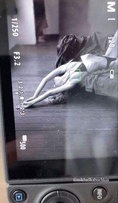 a cell phone with an image of a woman laying on the floor