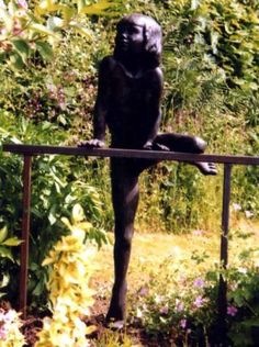 a black statue sitting on top of a wooden fence