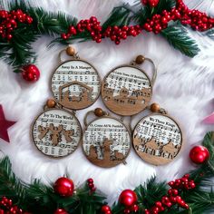 four wooden christmas ornaments with reindeers and musical notes on them, surrounded by holly branches