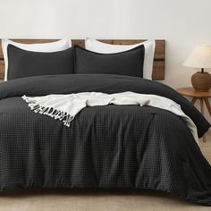 a bed with black and white comforter in a bedroom next to a night stand