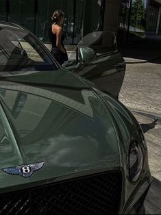 a woman standing next to a green sports car