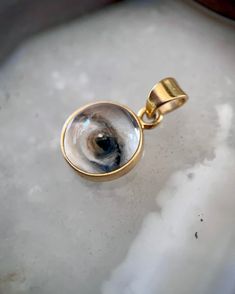 Lover's Eye pendant with an oil painting encased in gold plate over sterling with a quartz crystal cabochon which gives a magical magnifying effect, measuring 1/2" in diameter; 18" 16k gold over brass chain included. THE HISTORY: Lover's Eyes were a jewelry trend c.1785-1830 of brooches set with tiny watercolor portraits on ivory. Since they were cropped to eyes, they were in many ways more direct and intimate than traditional miniature portraits; but also because they were just eyes, they were Mystical 14k Gold Jewelry Gift, Mystical 14k Gold Jewelry, Mystical Engraved Gold Jewelry, Gold Mystical Jewelry For Anniversary, Mystical Gold Jewelry For Anniversary, Spiritual 14k Gold Keepsake Jewelry, Spiritual Gold Cabochon Necklace, Gold Spiritual Necklace With Cabochon, Gold Spiritual Jewelry For Keepsake