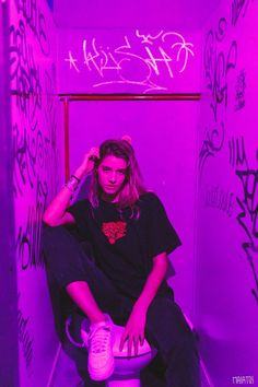 a woman sitting on top of a toilet in a room with graffiti all over the walls