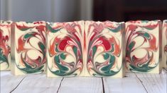 four different colored blocks sitting on top of a wooden table with white and red designs