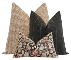 three decorative pillows sitting next to each other on top of a white surface with black and brown accents