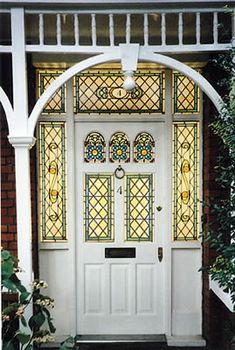 a white front door with stained glass panels and arched window above the entrance to a house