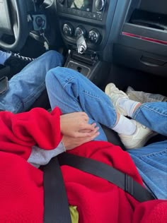 a person sitting in the driver's seat of a car with their feet on the steering wheel