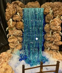 a blue waterfall is surrounded by rocks and streamers in front of a black backdrop