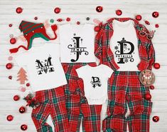 christmas pajamas and onesuits are laid out on a white wooden surface with ornaments around them