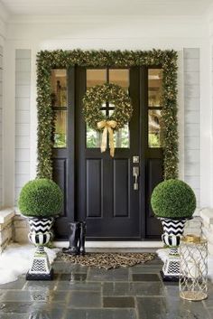 the front door is decorated with wreaths and potted plants