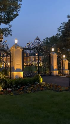 an iron gate is lit up at night in front of the entrance to a mansion