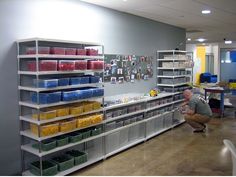 a man kneeling down in front of a shelf filled with plastic containers and other items