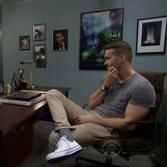 a man sitting in an office chair with his feet up on the desk while talking on the phone