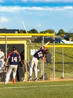 the baseball players are trying to catch the ball in the air while others look on