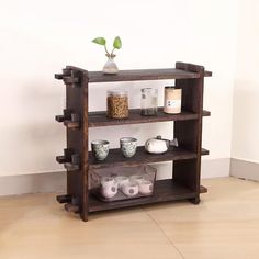 a wooden shelf with cups and mugs on it in front of a white wall