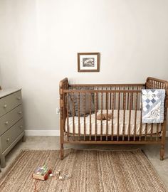 a baby's crib in the corner of a room with a dresser and mirror