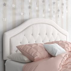 a white bed topped with pillows and pink comforter next to a wall covered in stars