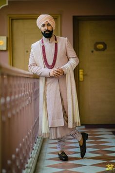 a man in a turban standing next to a railing with his hands on his hips