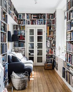 a living room filled with lots of books on top of a hard wood flooring