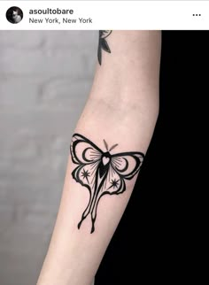 a black and white butterfly tattoo on the left arm, with an arrow in the middle