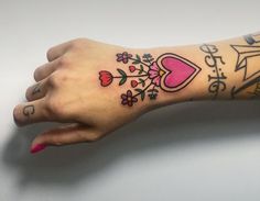 a woman's arm with tattoos on it and flowers in the middle, including hearts