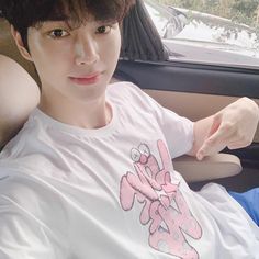 a young man sitting in the back seat of a car wearing a white t - shirt