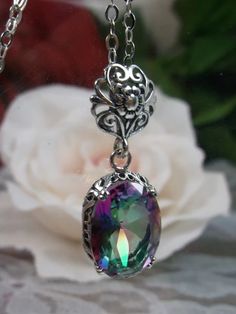 This is an Edwardian reproduction pendant style necklace in sterling silver filigree with a beautiful simulated Mystic Topaz stone. This oval gem is 14mm in length and 10mm in width. The pendant is 27mm long and 11mm wide. Notice the beautiful leaf design of the filigree and the Victorian filigree bail. This is a lovely rendition of antique filigree jewelry. The sterling silver chain (if chosen) is between 18-20" long. The pendant is marked 925 for solid sterling silver. Elegant Iridescent Oval Pendant Jewelry, Elegant Iridescent Round Pendant Jewelry, Mystic Topaz Necklace, Edwardian Necklace, Gem Pendant, Floral Filigree, Filigree Pattern, Order Design, Filigree Necklaces