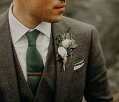 a man wearing a suit and tie with a boutonniere on his lapel