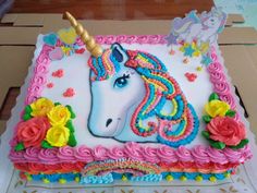 a birthday cake with a unicorn face and flowers on the side, sitting on top of a cardboard box