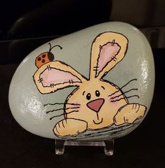 a painted rock with a rabbit and ladybug sitting on it's side