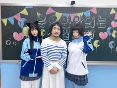 three people standing next to each other in front of a blackboard