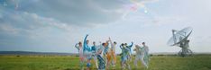 a group of people standing on top of a lush green field next to a satellite dish