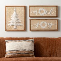 three wall hangings on the wall above a couch with a pillow and two pillows