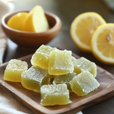 sliced lemons on a wooden cutting board next to bowls with oranges in the background