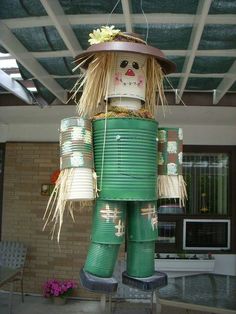 a large green tin can with a scarecrow on it's head and legs