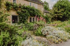 an old stone house surrounded by greenery and flowers