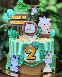 a two tiered cake decorated with animals and jungle decorations on top of a table