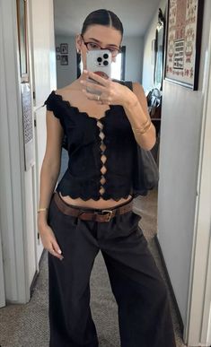 a woman taking a selfie with her cell phone in front of her face and wearing black pants