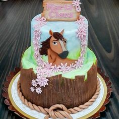 a horse themed birthday cake with flowers on the top and bottom, sitting on a wooden table