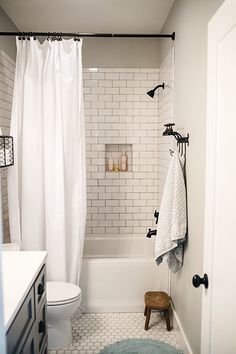 a white bathroom with black and white accessories on the shower curtain, rug, and bathtub