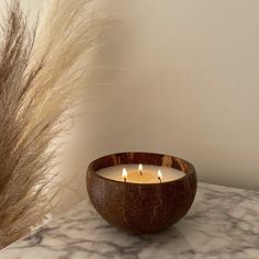 a wooden bowl sitting on top of a table next to a tall dry grass plant