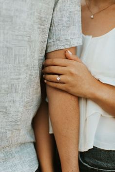 two people holding each other's hands with their arms wrapped around one another and the other hand behind them